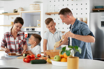  Mother and father making breakfast with sons. Young family preparing delicious food in kitchen.