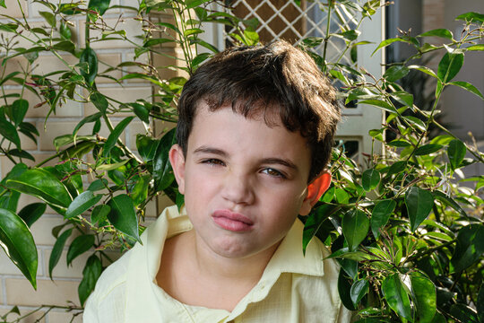 Close-up of a 7-year-old Brazilian child, finding it bad because it is in the middle of the foliage.