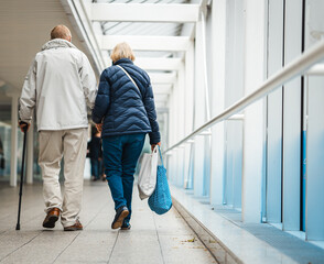Old couple from behind holding each others hand on a walk
