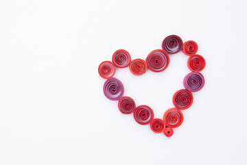 Heart from colored paper ribbons on a white background in the style of quilling.