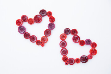 Hearts from colored paper ribbons on a white background in the style of quilling.