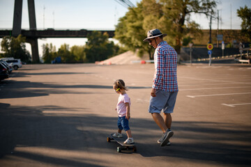 view of little girl riding skateboard while her father walks beside