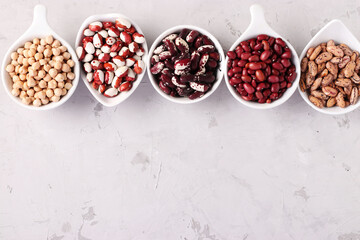 Four varieties of beans and chickpea - protein rich beans are located on a gray concrete background, Top view, Space for text