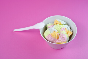 multicolored ice cream in a white bowl on a pink background.