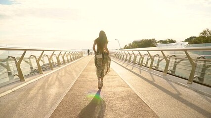 Portrait of happy young woman walking across the bridge in the city - Powered by Adobe