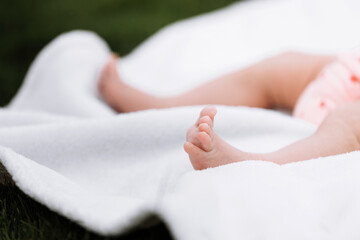 Fototapeta na wymiar Closeup of newborn baby girl feet on white blanket outdoor. maternity and childhood concept
