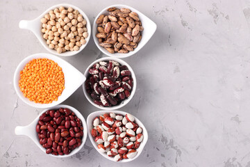 Four varieties of beans, red lentils and chickpeas - protein rich beans are located on a gray concrete background, Top view