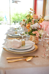 Elegant table setting with gold accents and red wall, clear chairs and flowers