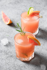 Two rosemary grapefruit sodas on light grey. Vertical format. Close up. Mocktail Paloma. 