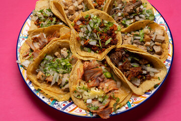 Assortment of mexican tacos on pink background