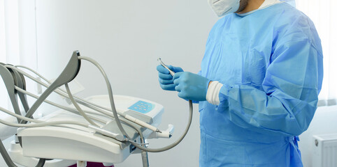 Photo of a dentist surgeon in surgical suit holding a dental drill and prepare for dental implant...