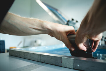 Selective focus of man holding squeegee while working on screen printing press in workshop 