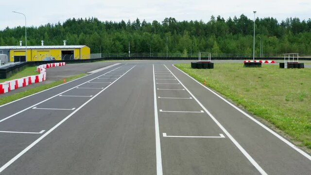 Aerial view drone flies over empty race track. Speed races track from above. Cloudy summer day. Go-karts race way by green forest in nature