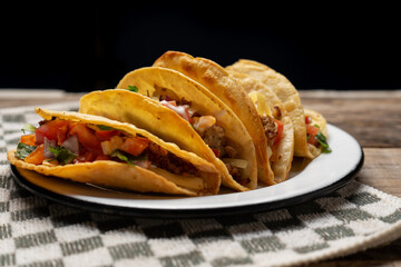Mexican hard-shell tacos with meat and fresh sauce on wooden background