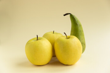 yellow golden delicious apples and a pear on a yellow background