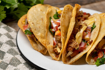 Mexican hard-shell tacos with meat and fresh sauce on wooden background