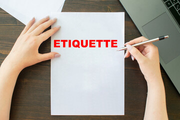 ETIQUETTE inscription on sheet a4, the girl writes next to the laptop