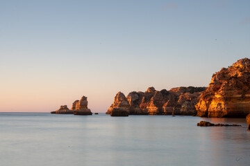 Scenic Algarve cliffs in the sunrise. Calm ocean, long shutter speed. Early morning. Lagos, Algarve Coast, Portugal