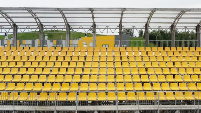 Aerial view drone flies over empty stadium or race track seats during coronavirus COVID-19 pandemic. Rows and yellow seats without viewers and spectators