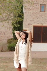 joven mujer latina de cabello ondulado con vetido marron disfrutando del campo