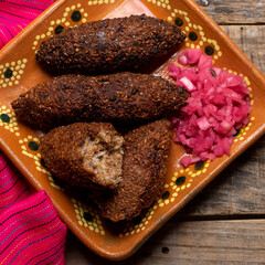 Mexican kibi with meat and onion on wooden background