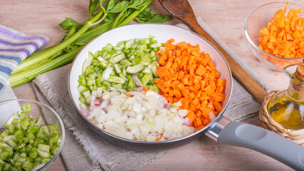 Cooking carrot and celery onion vegetable dressing, chopped ingredients for Mirepoix or Soffritto in a skillet