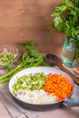 Cooking carrot and celery onion vegetable dressing, chopped ingredients for Mirepoix or Soffritto in a skillet