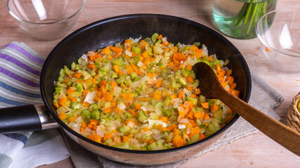 The preparation of fried vegetable filling of onions carrots and celery - ready Mirepoix or Soffritto  in a frying pan.