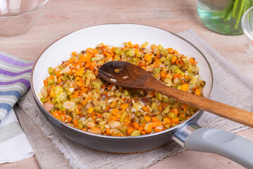 The preparation of fried vegetable filling of onions carrots and celery - ready Mirepoix or Soffritto  in a frying pan.