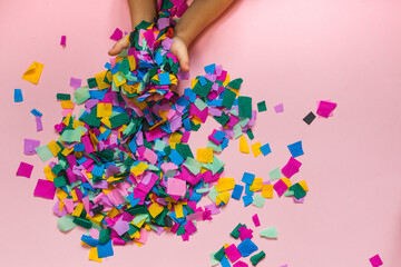 children's hands throwing colorful confetti. top view on a pink background