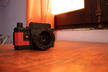 black and red plastic analog camera on a wooden cabinet. vintage camera