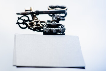 Vintage keys and a piece of white sheet of paper on a white background, high key, there is a place for an inscription