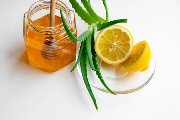 Useful ingredients for strengthening the immune system on a white background.Honey in a jar, lemon and aloe Vera. Space for text
