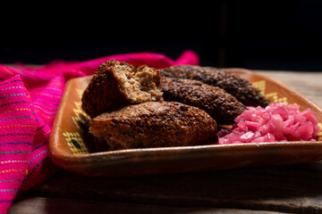Mexican kibi with meat and onion on wooden background