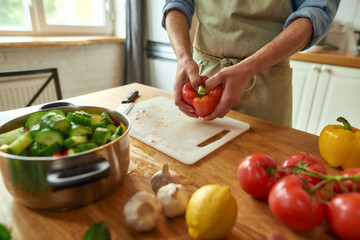 Close up of hands of man preparing pepper to use in cooking healthy meal, soup in the kitchen. Italian cuisine concept