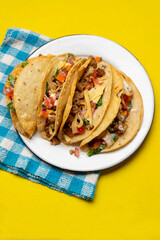 Mexican hard-shell tacos with meat and fresh sauce on yellow background