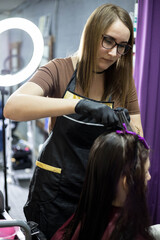 A hairdresser girl does her hair for her client in a beauty salon