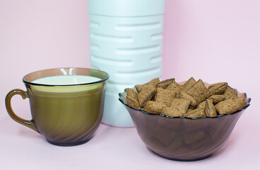 Breakfast dried chocolate pads on pink background with milk. Healthy tasty breakfast chocolate square pads.
