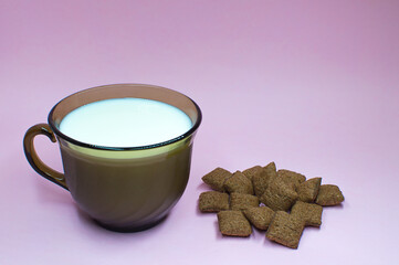 Breakfast dried chocolate pads on pink background with milk. Healthy tasty breakfast chocolate square pads.