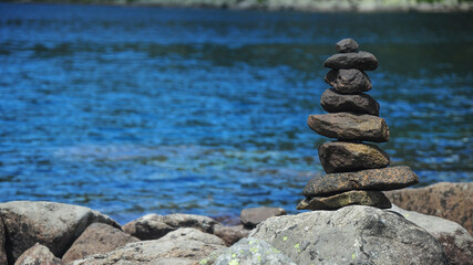 Fototapeta na wymiar Equilibrium. Stone tower built on the shoreof bucura glacial lake.
