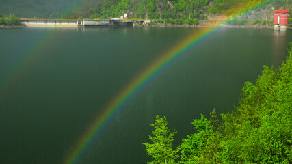 Double rainbow in a rainy day over Bradisor lake in summer season. Lotru Mountains, Carpathia, Romania.