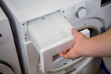 clothes dryer water tank, man maintains the machine regularly, empties the water tank, cleans the...