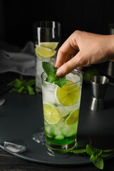 Woman making fresh mojito at table