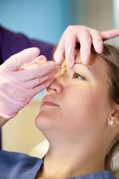 Woman recieving anti-aging injections in her forehead.