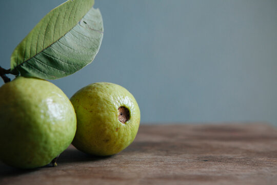 Two guavas on a wooden table with copyspace.