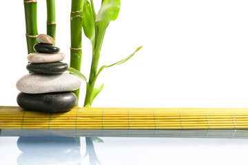 Stack of spa stones and bamboo near lake on white background