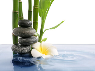 Fototapeta na wymiar Stack of spa stones, flower and bamboo in water on white background