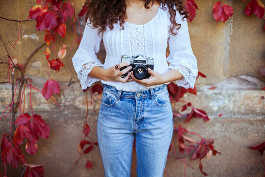 Beautiful young woman with curly hair, blue eyes and freckles holding a vintage camera