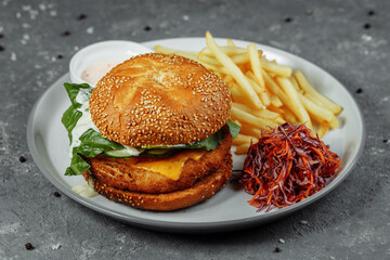 chicken burger with french fries and salad on an old concrete background
