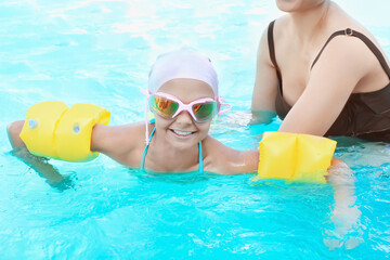 Coach teaching little child to swim in pool